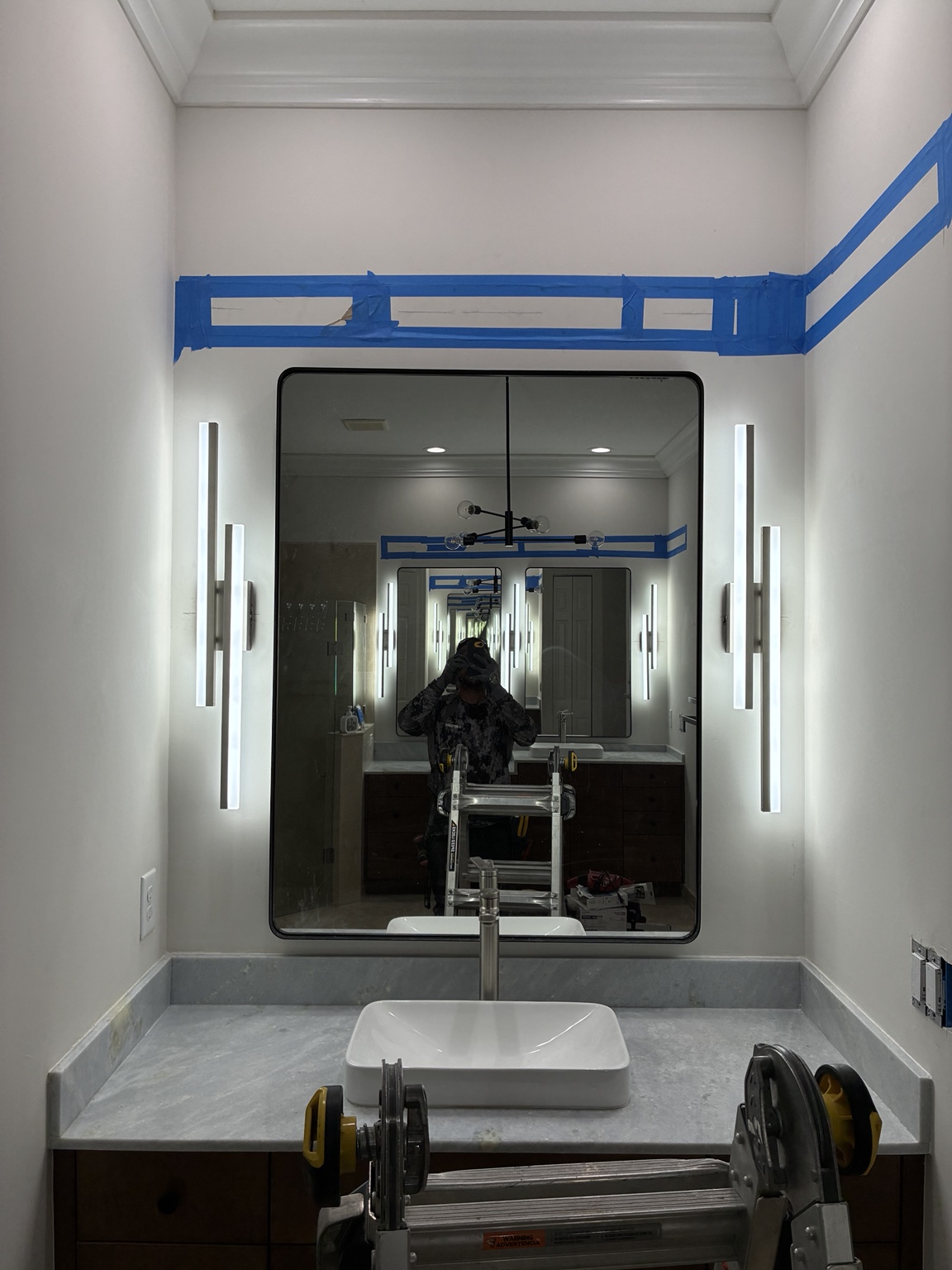 After — illuminated sconces installed around the single vanity