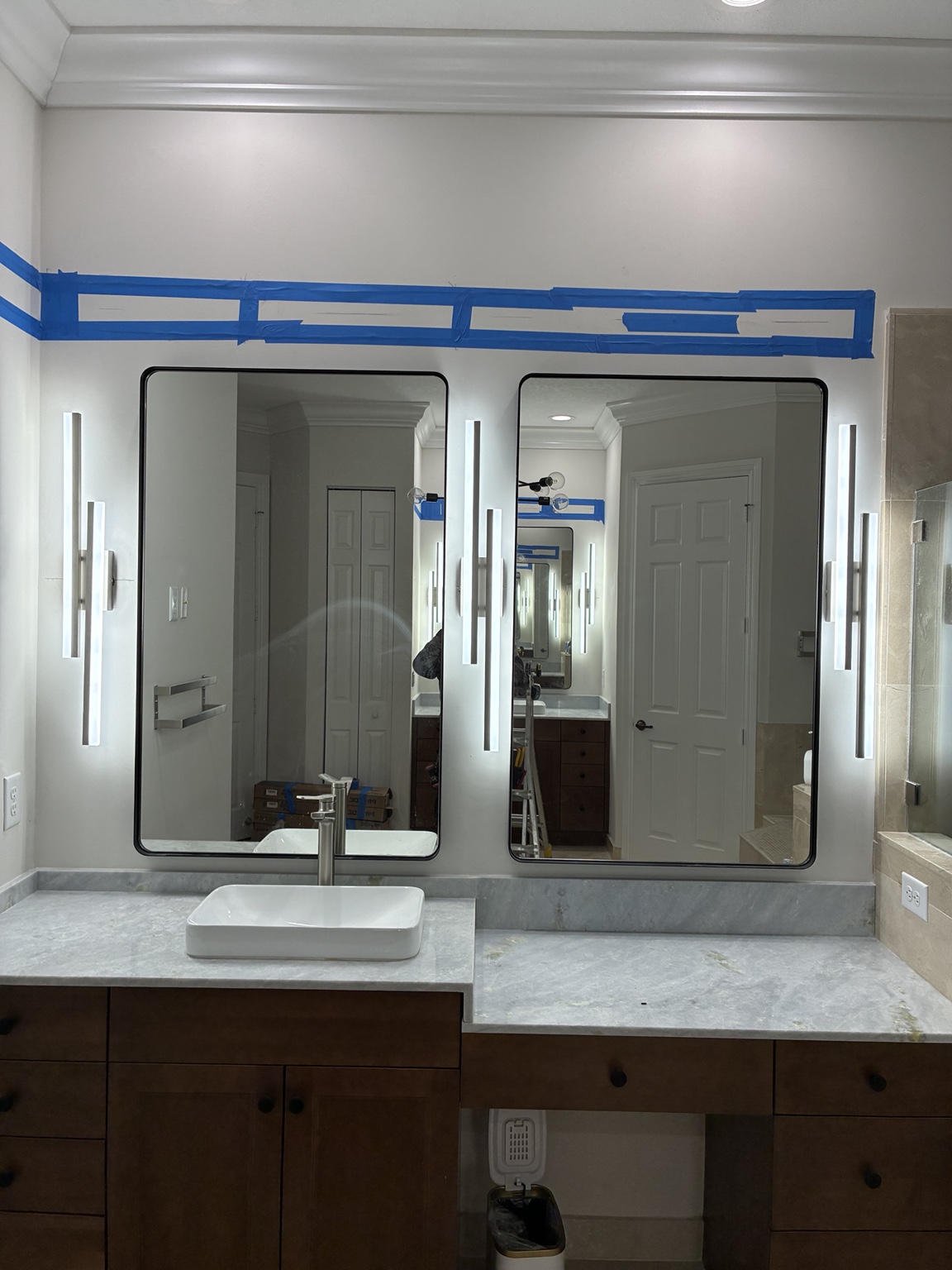 After — illuminated sconces installed around the double vanity